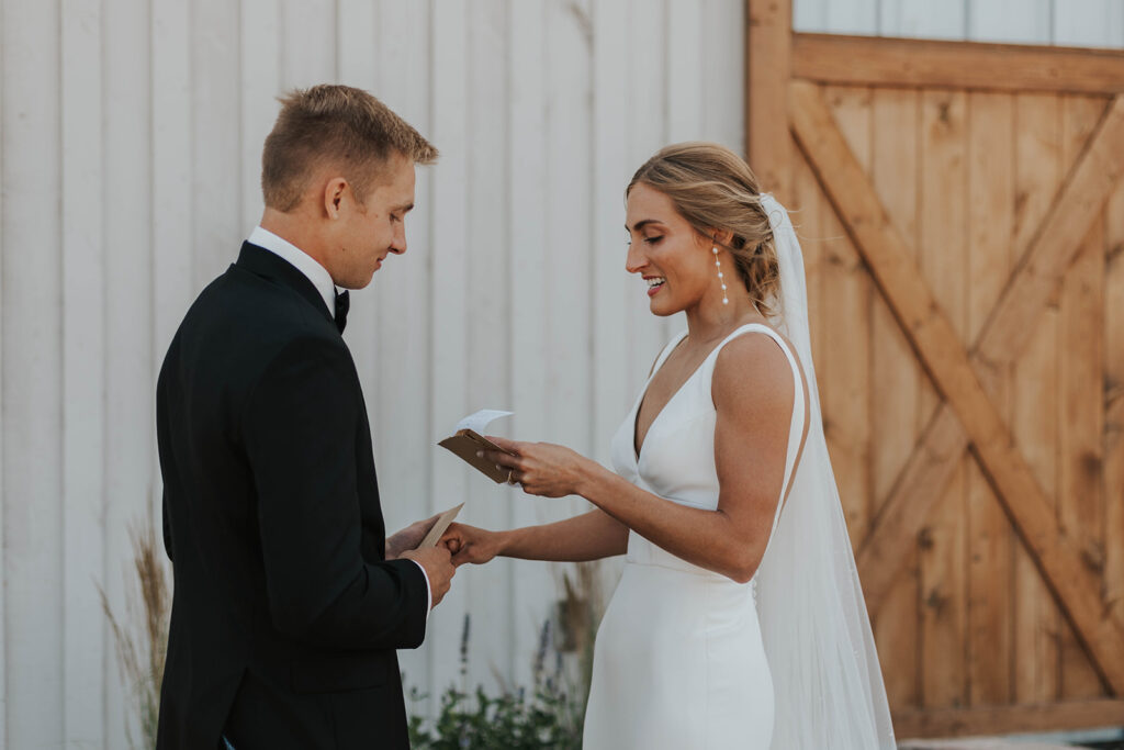 bride and groom exchanging private vows with a rustic barn wedding venue in the backdrop