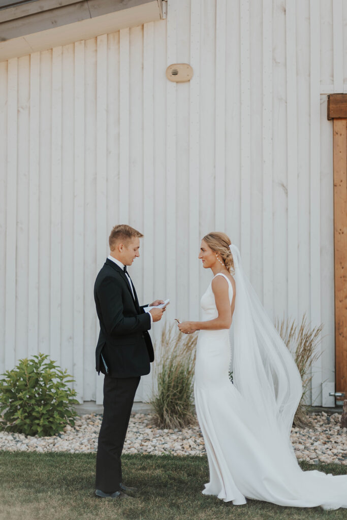 bride and groom exchanging private vows with a rustic barn wedding venue in the backdrop