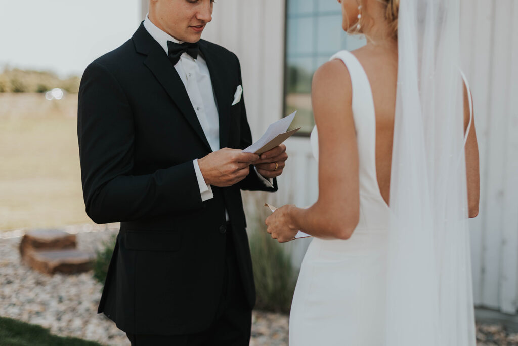 bride and groom exchanging private vows with a rustic barn wedding venue in the backdrop