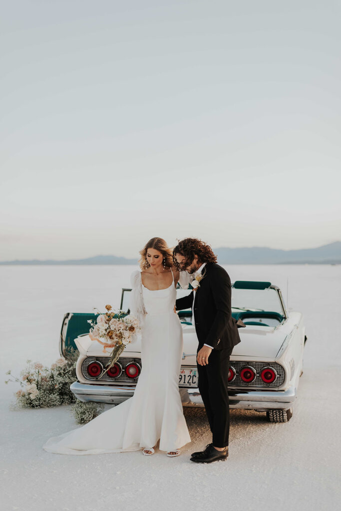 bride and groom posing by their classic car rented for their bonneville salt flats elopement