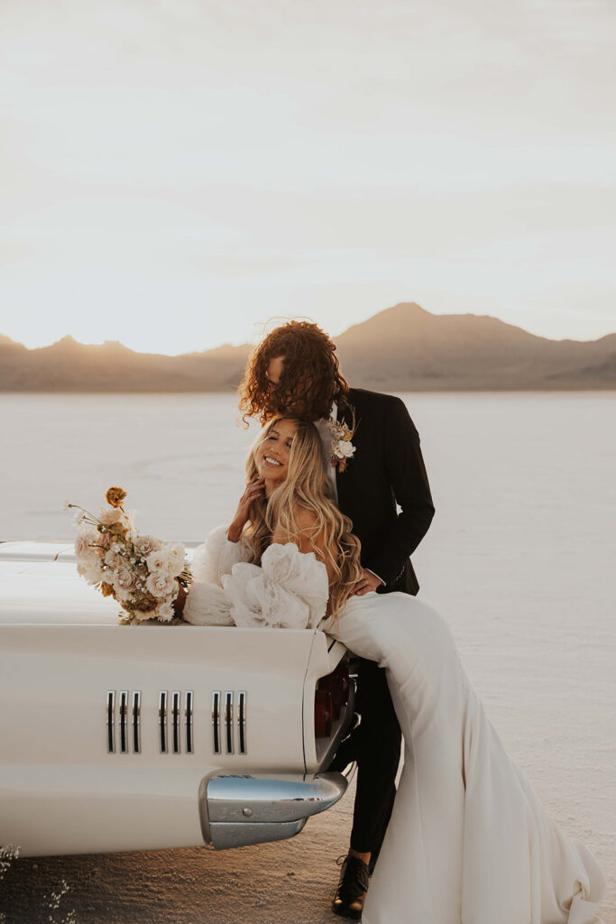 bride and groom posing by their classic car rented for their bonneville salt flats elopement