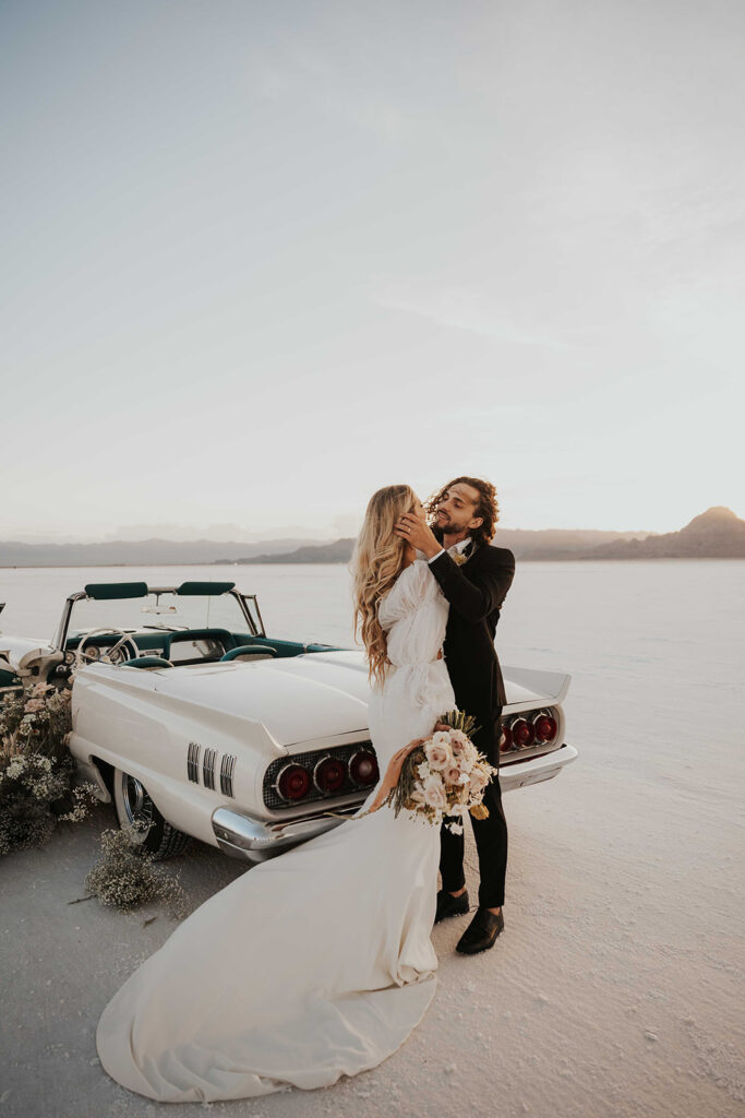 bride and groom posing by their classic car rented for their bonneville salt flats elopement