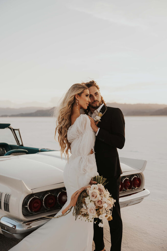 bride and groom posing by their classic car rented for their bonneville salt flats elopement