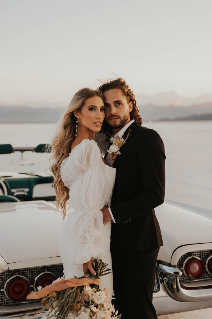 bride and groom posing by their classic car rented for their bonneville salt flats elopement