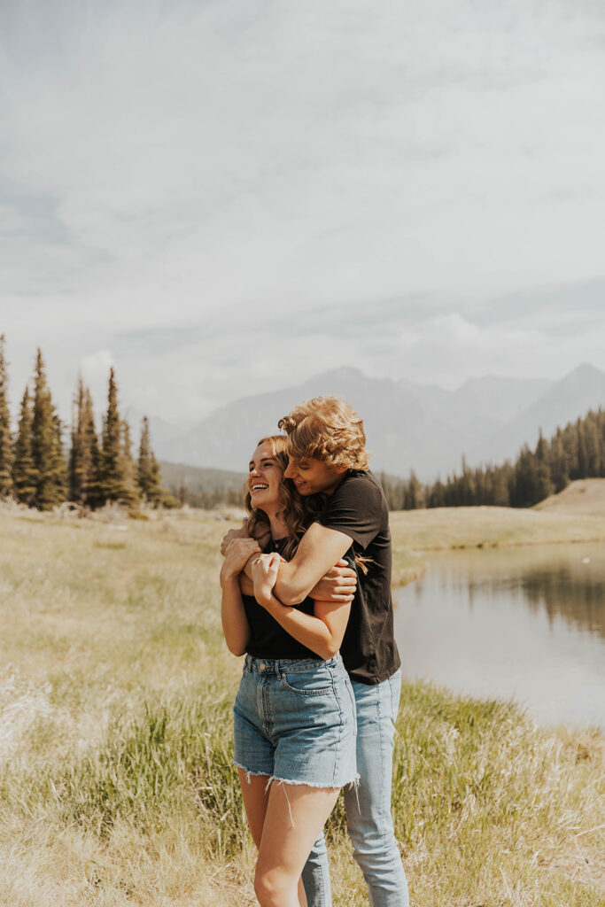 future bride and groom playing around in the field for their banff engagement photos