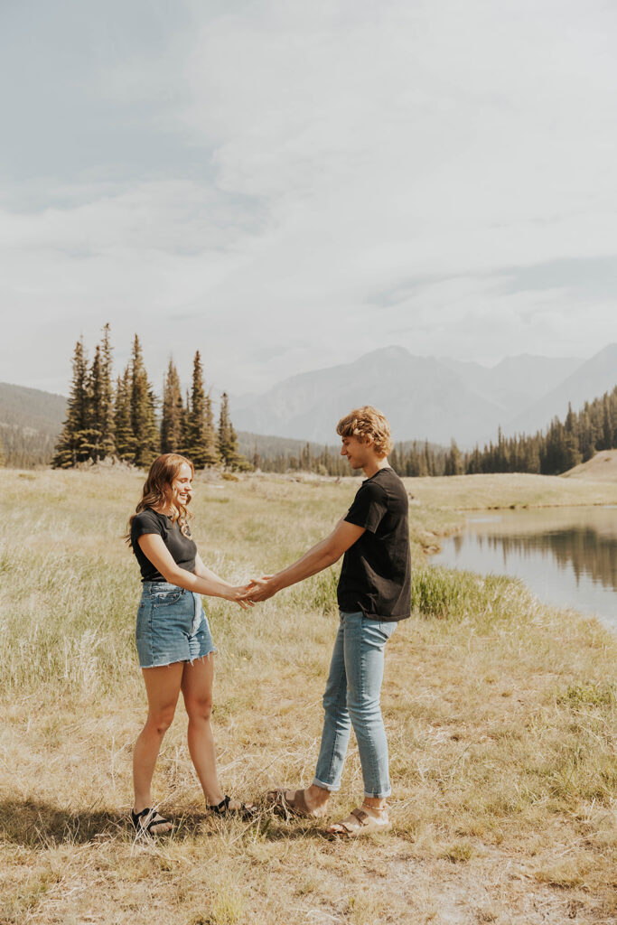 future bride and groom playing around in the field for their banff engagement photos