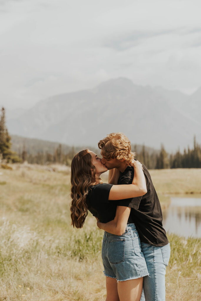 future bride and groom playing around in the field for their banff engagement photos