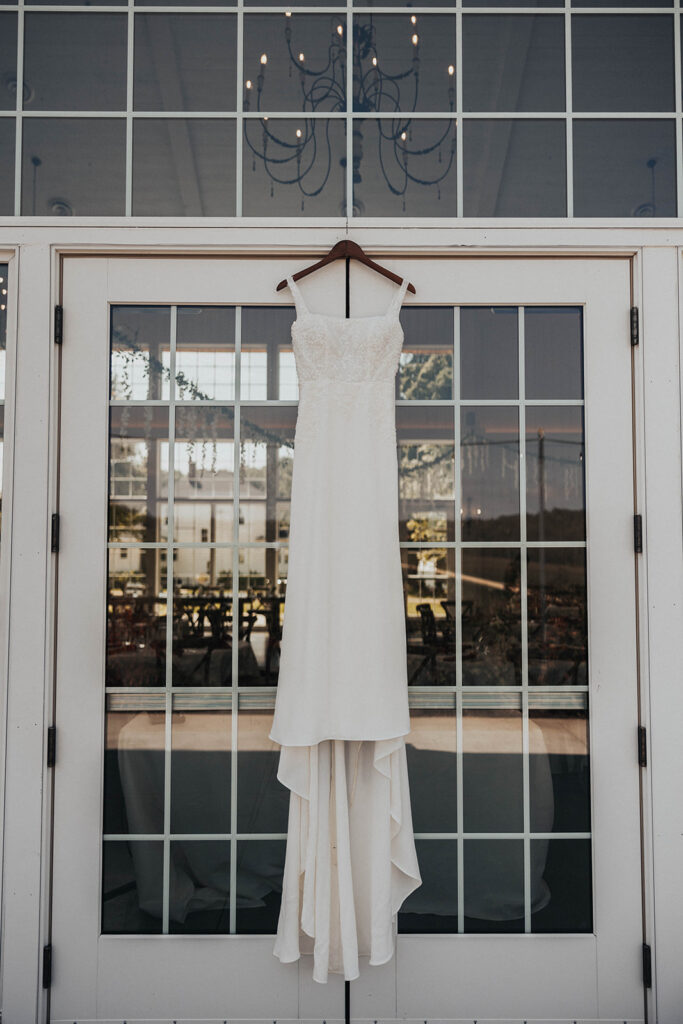 wedding dress hanging on a glass door