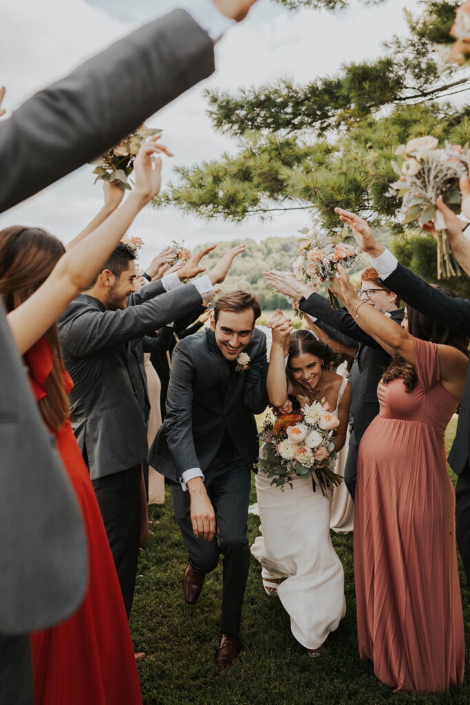 bride and groom running through a hand tunnel created by the wedding party