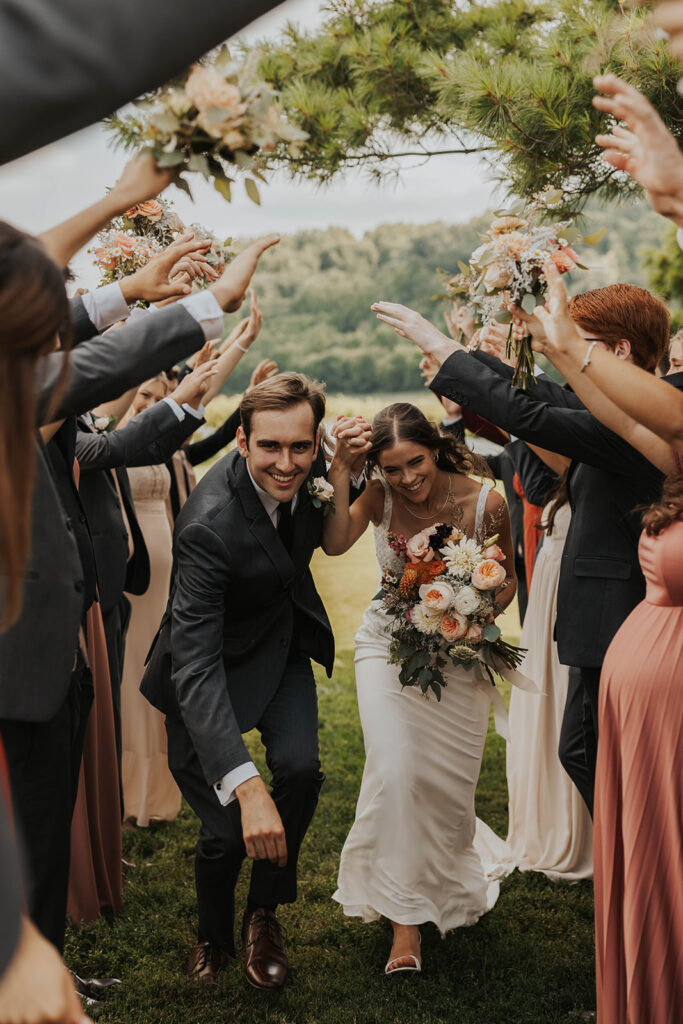 bride and groom running through a hand tunnel created by the wedding party