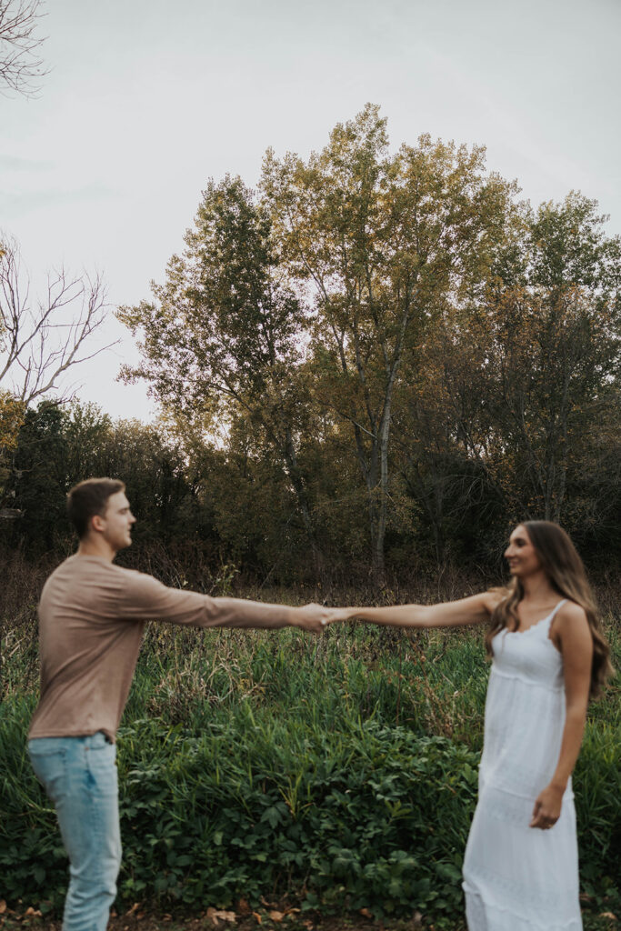 Sienna and Wyatt kissing each other playing around in a park for their fall engagement session