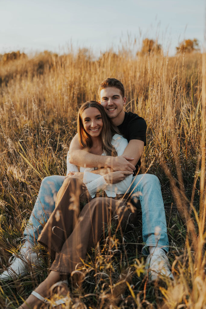 romantic engagement photos of Sienna and Wyatt sitting in a golden field