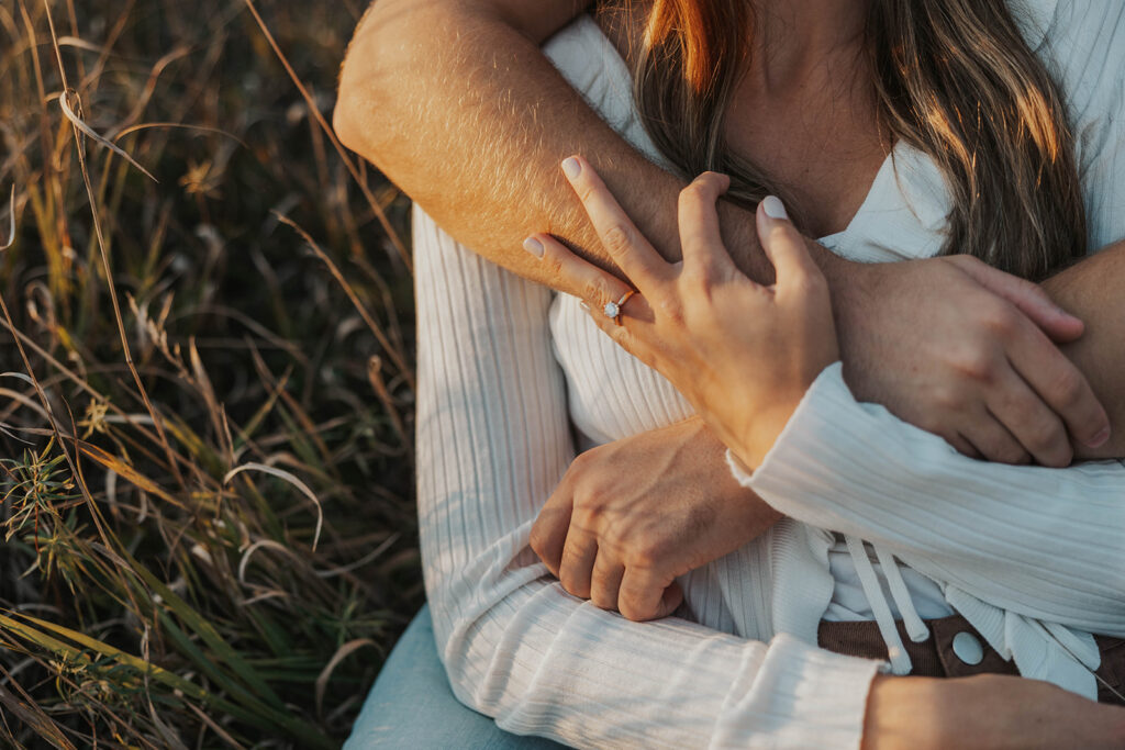 romantic engagement photos of Sienna and Wyatt sitting in a golden field