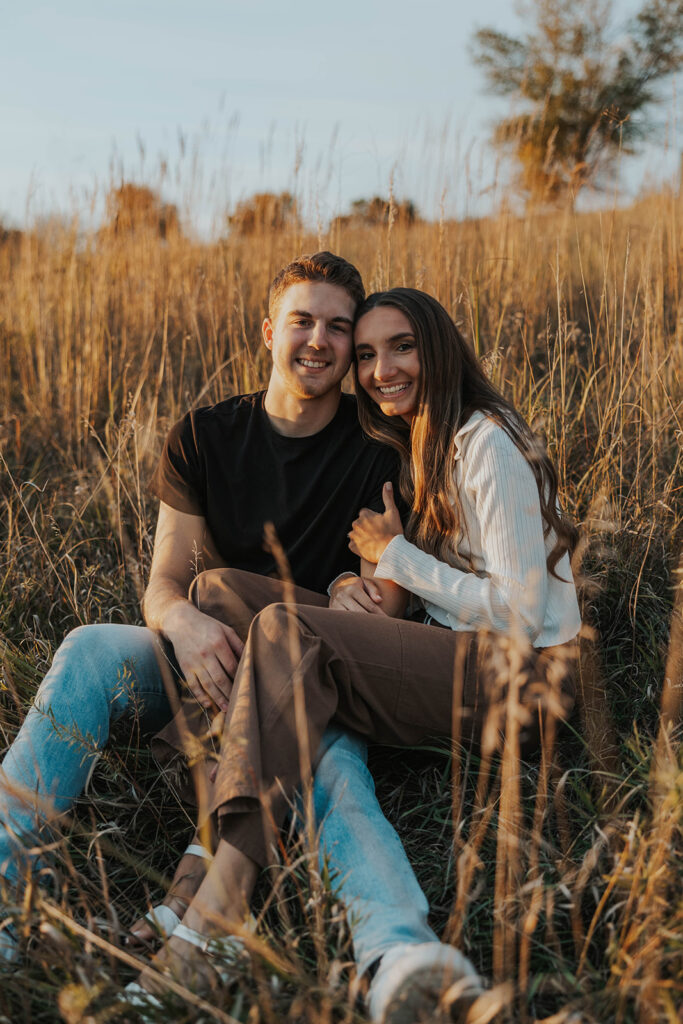 romantic engagement photos of Sienna and Wyatt sitting in a golden field