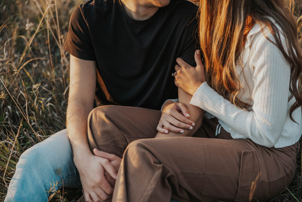 romantic engagement photos of Sienna and Wyatt sitting in a golden field