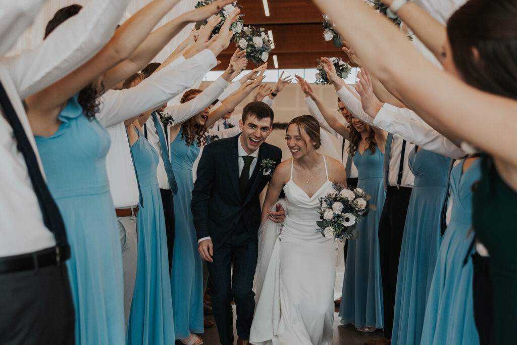 bride and groom running under a wedding party hand bridge 