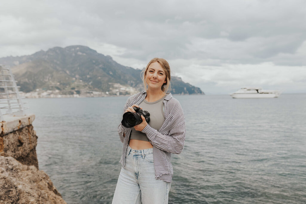 a photographer posing at Amalfi Coast with the Mediterranean Sea in the backdrop