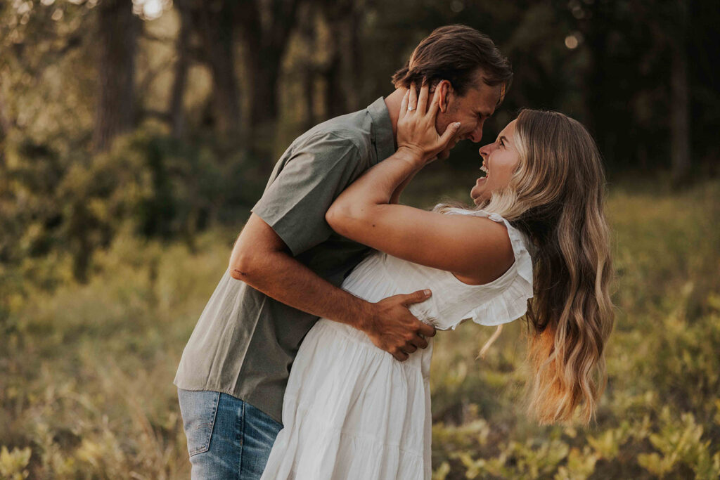 engaged couple laughing in a field during their minnesota engagement session