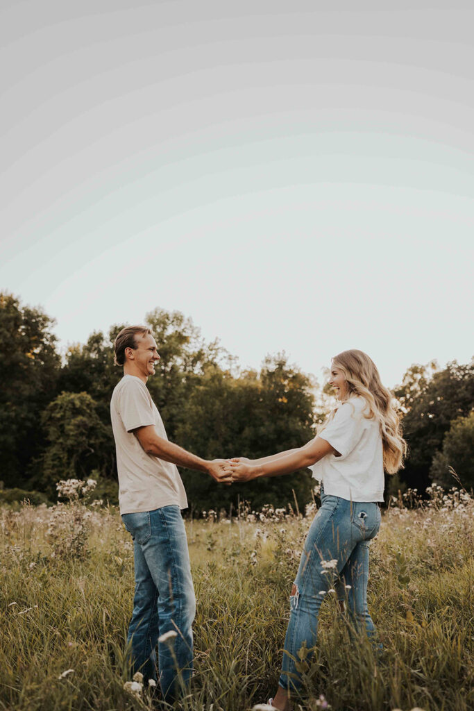 a cute and playful couple in a field during their Minnesota engagement session in Sibley State Park, captured by Cassie Beth: Minnesota Photographer