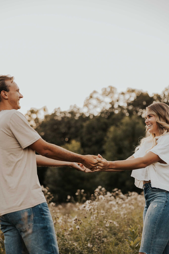 a cute and playful couple in a field during their Minnesota engagement session in Sibley State Park, captured by Cassie Beth: Minnesota Photographer