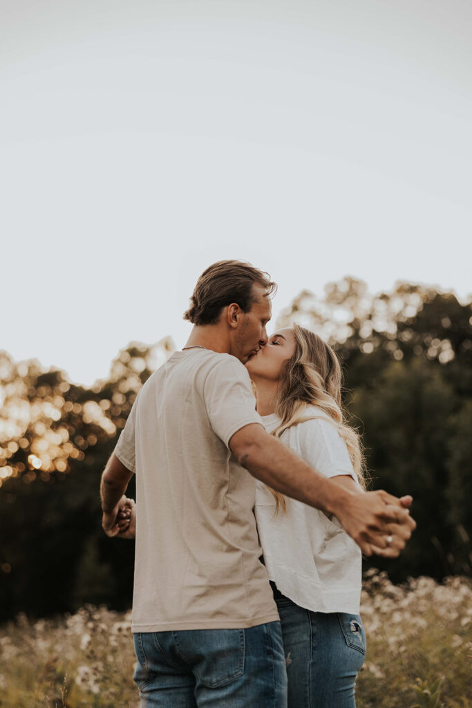 a cute and playful couple in a field during their Minnesota engagement session in Sibley State Park, captured by Cassie Beth: Minnesota Photographer