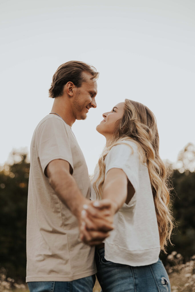 a cute and playful couple in a field during their Minnesota engagement session in Sibley State Park, captured by Cassie Beth: Minnesota Photographer