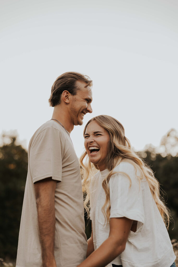 a cute and playful couple in a field during their Minnesota engagement session in Sibley State Park, captured by Cassie Beth: Minnesota Photographer