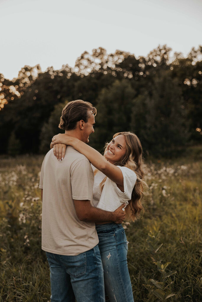 a cute and playful couple in a field during their Minnesota engagement session in Sibley State Park, captured by Cassie Beth: Minnesota Photographer