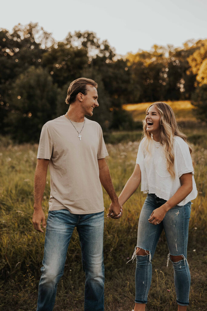 a cute and playful couple in a field during their Minnesota engagement session in Sibley State Park, captured by Cassie Beth: Minnesota Photographer