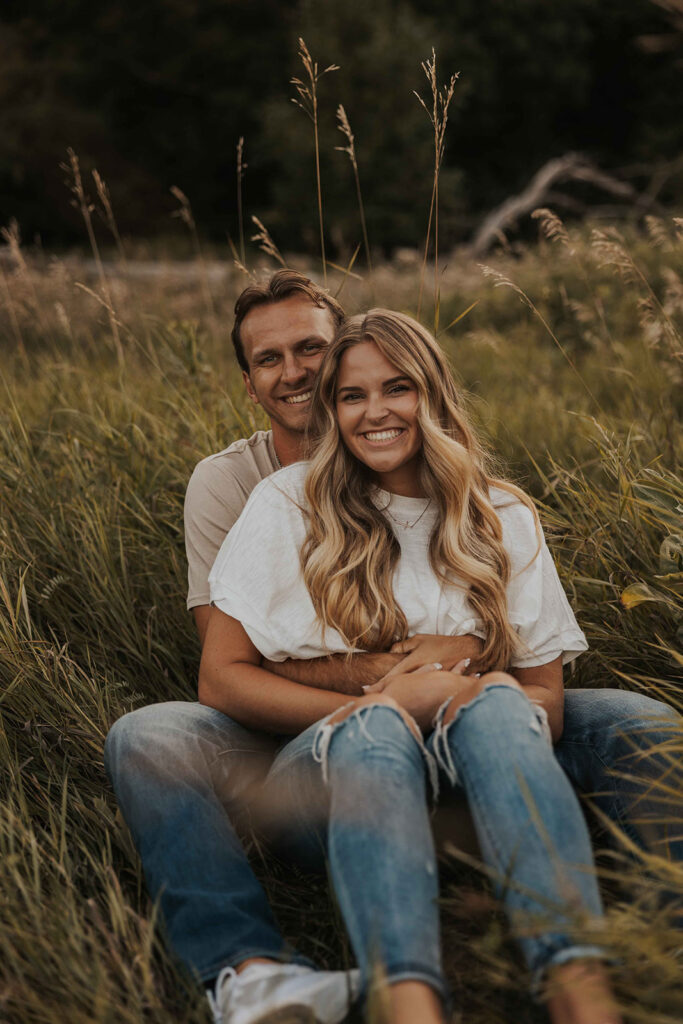 couple sitting in a grassy field in Sibley State Park during their engagement session. Captured by Cassie Beth: Minnesota Photographer