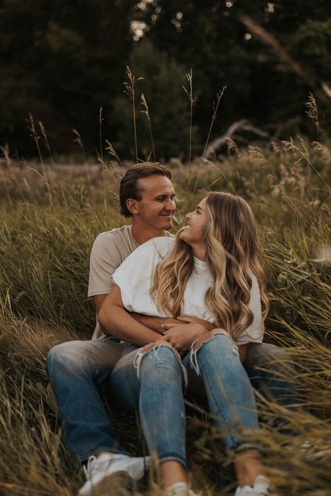 couple sitting in a grassy field in Sibley State Park during their engagement session. Captured by Cassie Beth: Minnesota Photographer