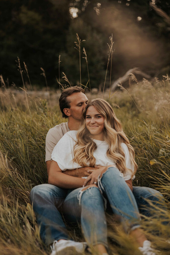 couple sitting in a grassy field in Sibley State Park during their engagement session. Captured by Cassie Beth: Minnesota Photographer