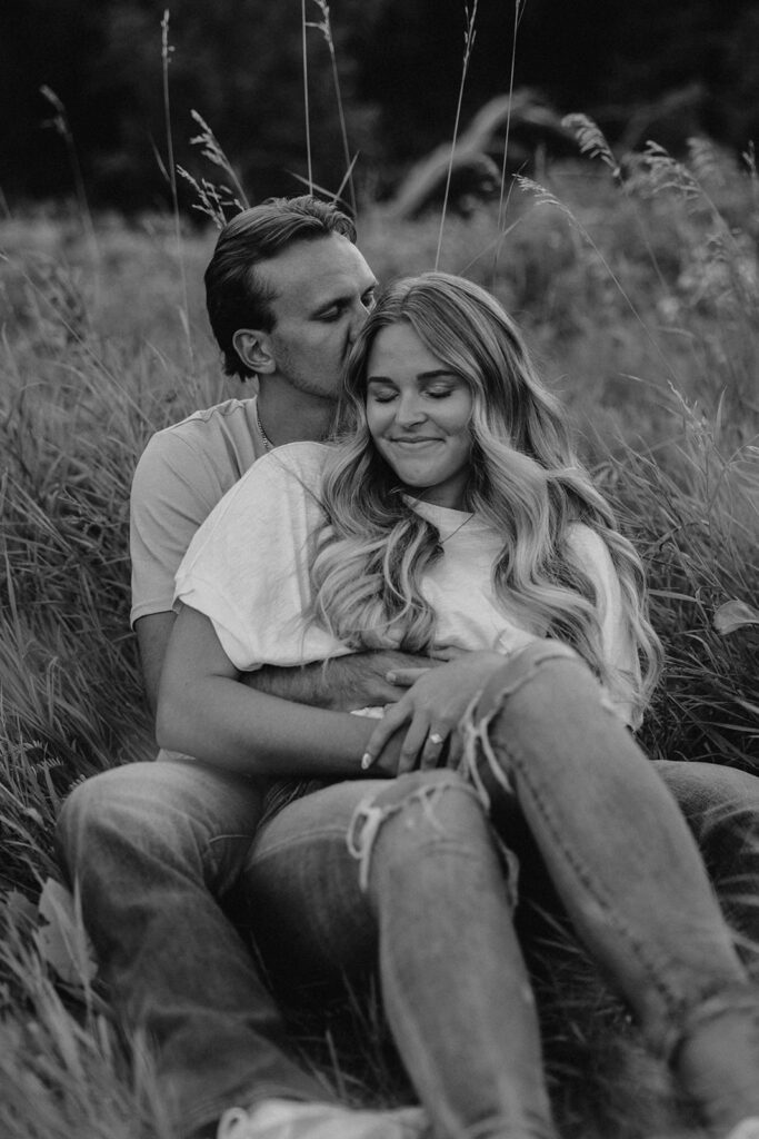 couple sitting in a grassy field in Sibley State Park during their engagement session. Captured by Cassie Beth: Minnesota Photographer