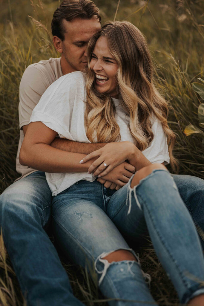 couple sitting in a grassy field in Sibley State Park during their engagement session. Captured by Cassie Beth: Minnesota Photographer