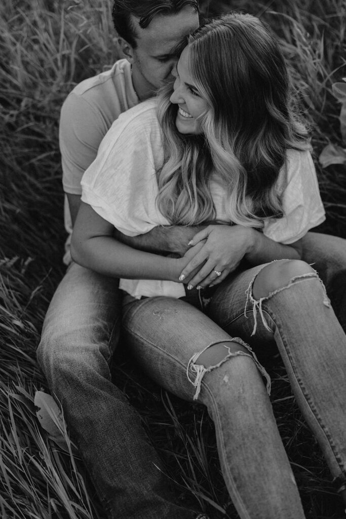 couple sitting in a grassy field in Sibley State Park during their engagement session. Captured by Cassie Beth: Minnesota Photographer