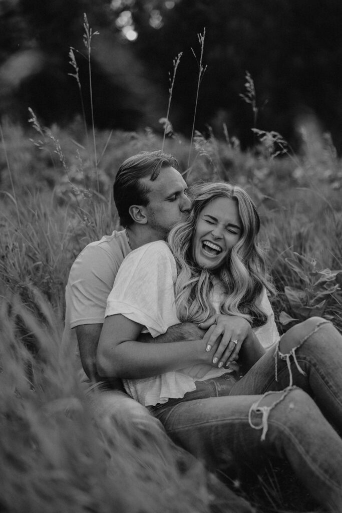 couple sitting in a grassy field in Sibley State Park during their engagement session. Captured by Cassie Beth: Minnesota Photographer