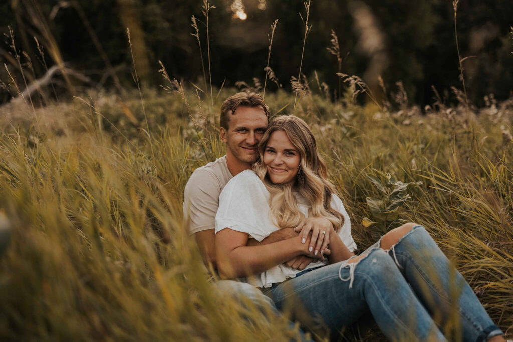 a cute and playful couple in a field during their Minnesota engagement session in Sibley State Park, captured by Cassie Beth: Minnesota Photographer