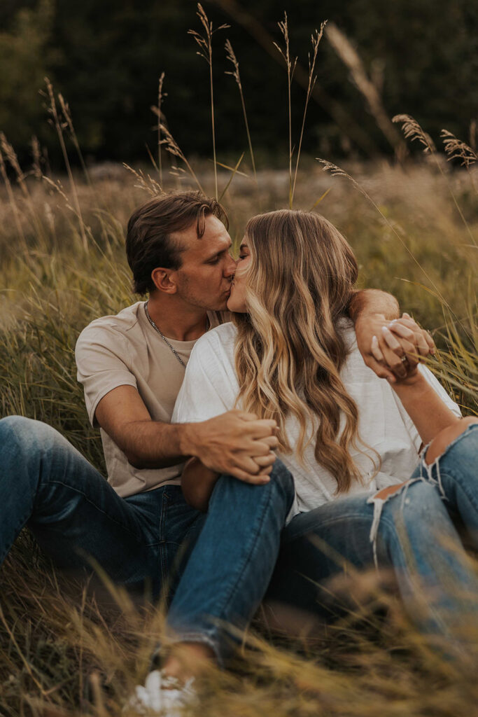 couple sitting in a grassy field in Sibley State Park during their engagement session. Captured by Cassie Beth: Minnesota Photographer