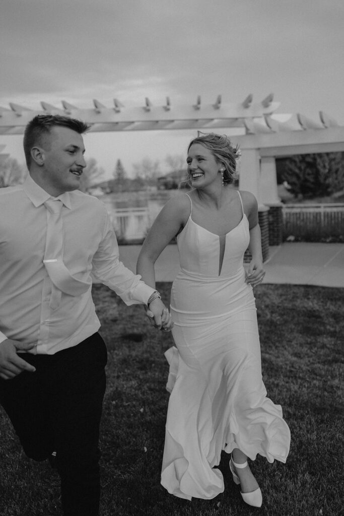 candid black and white photo of bride and groom running