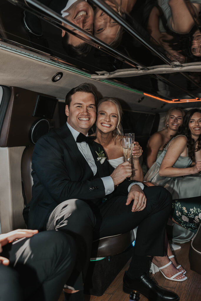 bride and groom and the wedding party celebrating in a limo