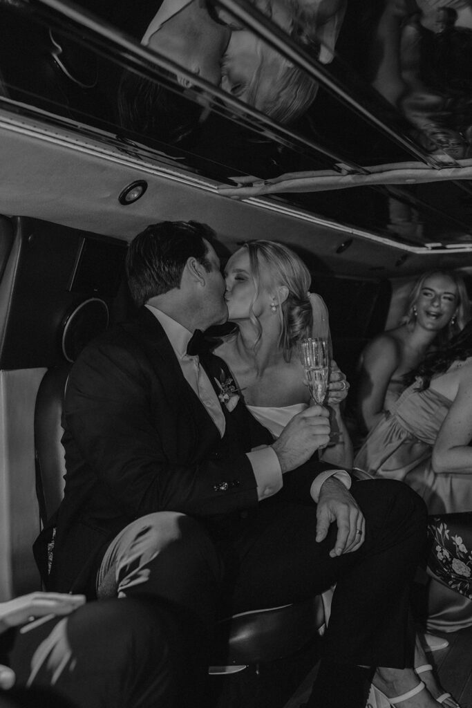 bride and groom and the wedding party celebrating in a limo