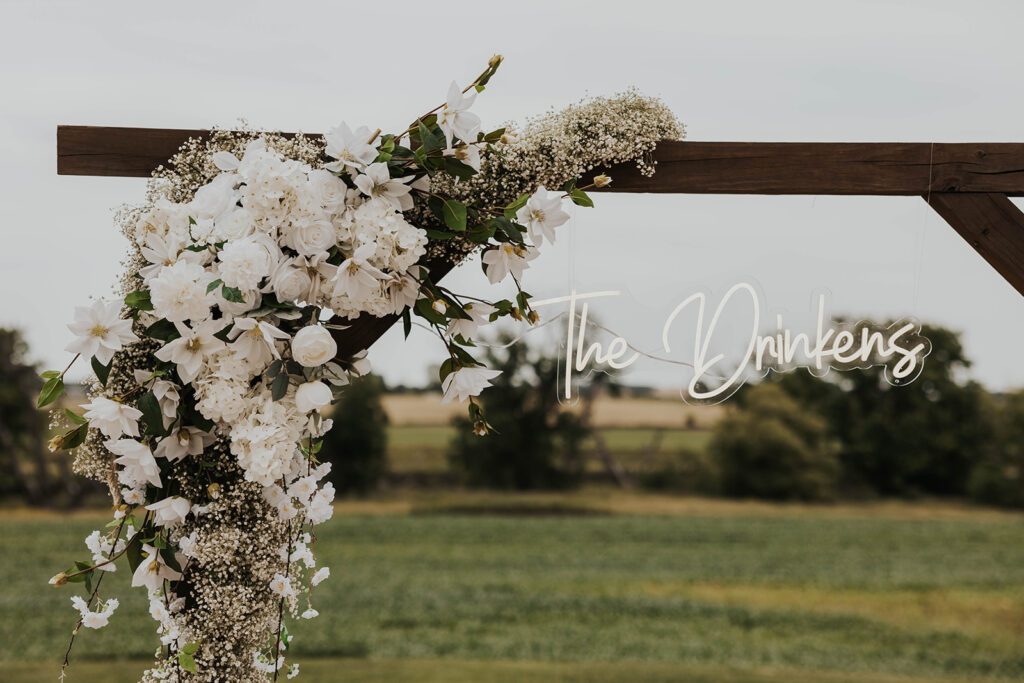 elegant wedding florals on a wooden arch with custom wedding signage