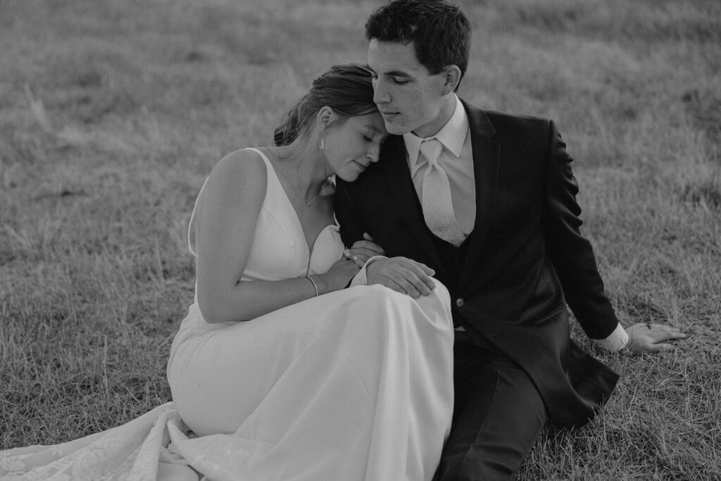 black and white intimate moment of bride and groom sitting in the grass at their Montana wedding location