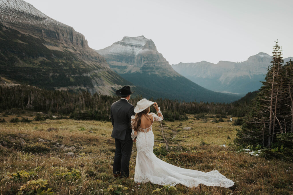 A bride and groom looking at mountains on the day of their wedding in Glacier National Park