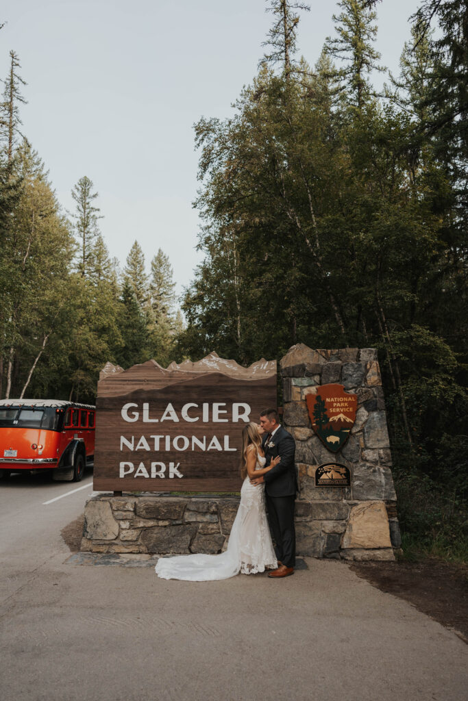 Couple kissing in front of the Glacier National Park entrance sign