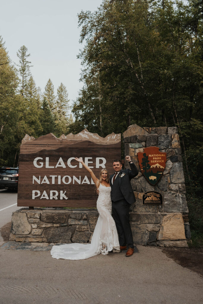 Couple celebrating getting married in front of the Glacier National Park entrance sign