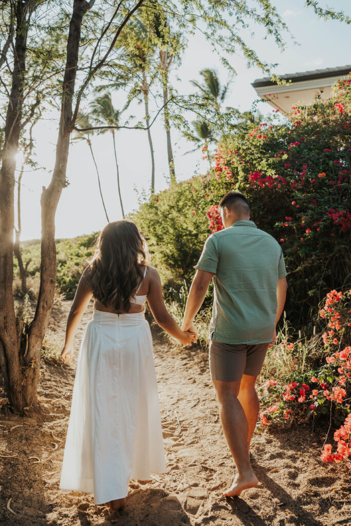 Couple walking on a sandy beach trail in Maui, Hawaii.