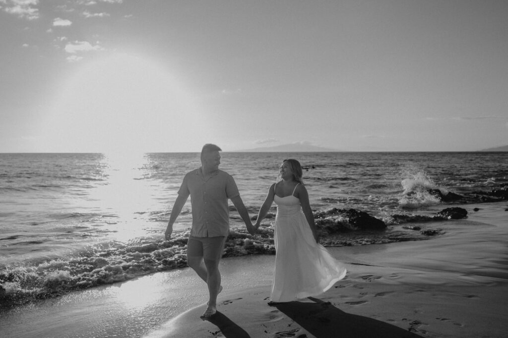 Black and white image of a couple holding hands on Po'olenalena Beach.