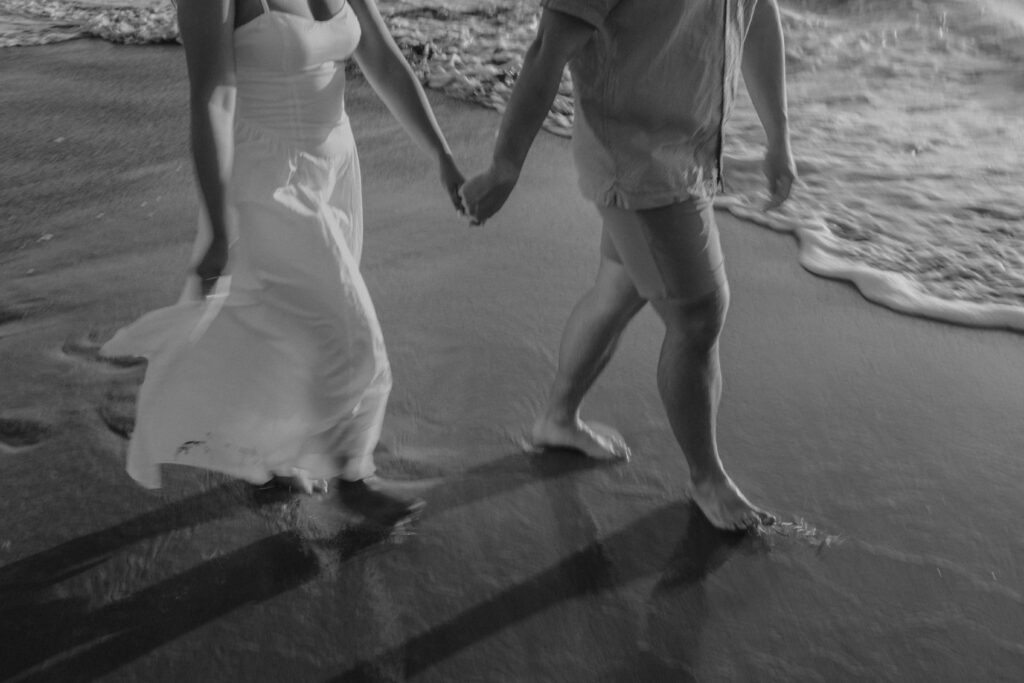 Couple walking and holding hands on a beach in Maui, Hawaii.