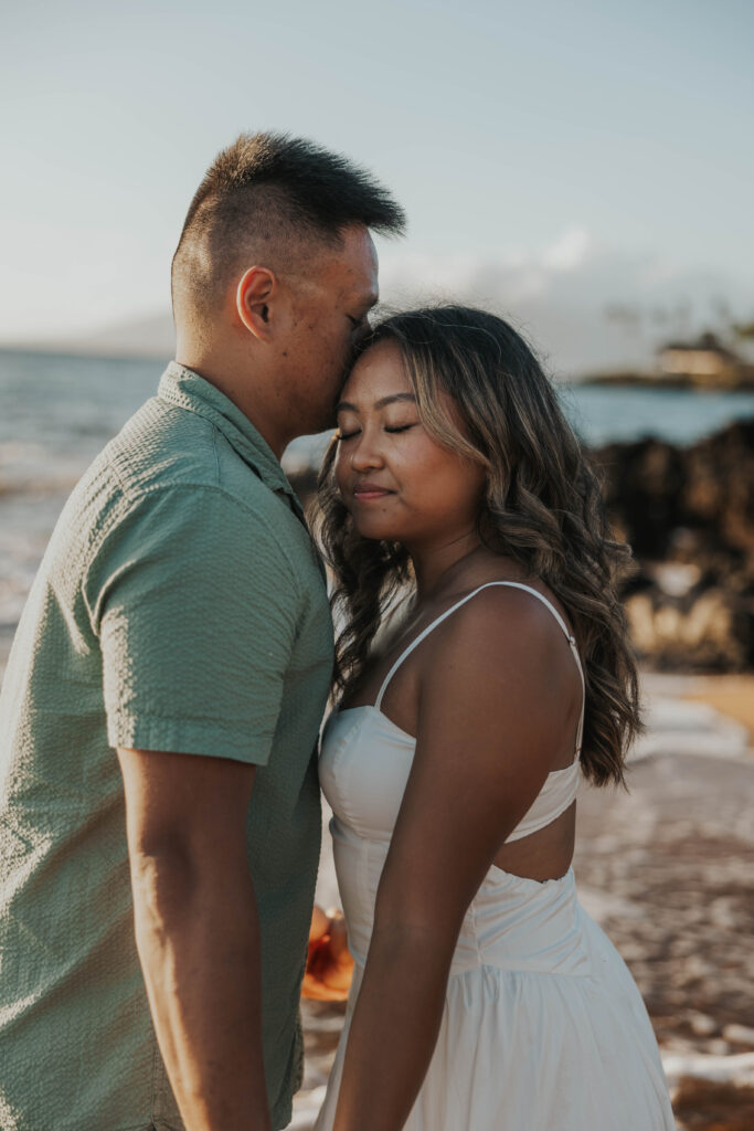 Candid couple in front of rocks on Po'olenalena Beach in Maui, Hawaii.